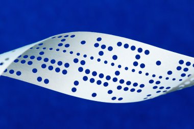 Closeup of perforated punched tape on blue background clipart