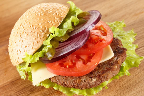 Traditional American cheeseburger. Meat, bun and vegetables close up