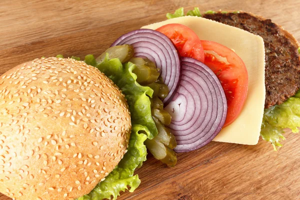 Hamburguesa tradicional americana con queso. Carne, bollo y verduras de cerca —  Fotos de Stock