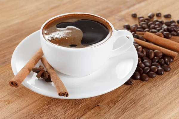 Coffee cup and beans, cinnamon sticks, anise on wooden table — Stock Photo, Image