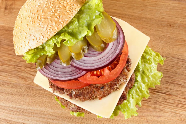 Traditionele Amerikaanse cheeseburger. Vlees, broodje en groenten close-up — Stockfoto