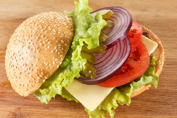 Traditional American cheeseburger. Meat, bun and vegetables close up