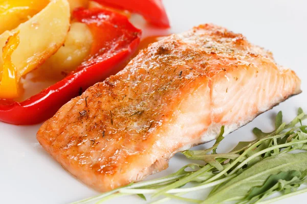 Grilled salmon fillet with vegetables, spices and arugula on a plate