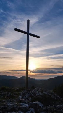 Dikey zaman çizelgesi güneşin demir bir dağ geçidinde battığını gösteriyor. Ilık altın ışınlar kayalık tepeleri ve uzak tepeleri aydınlatırken yumuşak bulutlar sakin akşam gökyüzünde yavaşça ilerler.