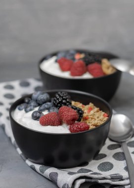 Seninle müsli ve koyu gri arka planda siyah kasede taze böğürtlen..