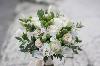 Gelin buketi. Gelinin buketi. Güzel bir buket beyaz, çiçekler ve yeşillik, uzun ipek kurdele ile süslenmiş gri dokuma arka planda yatıyor.