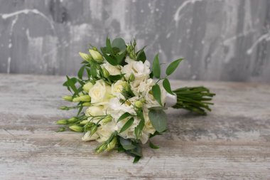 Gelin buketi. Gelinin buketi. Güzel bir buket beyaz, çiçekler ve yeşillik, uzun ipek kurdele ile süslenmiş gri dokuma arka planda yatıyor.