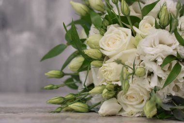 Gelin buketi. Gelinin buketi. Güzel bir buket beyaz, çiçekler ve yeşillik, uzun ipek kurdele ile süslenmiş gri dokuma arka planda yatıyor.