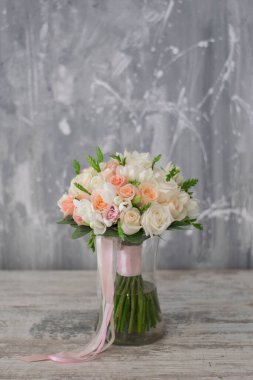 Gelin buketi. Gelinin buketi. Güzel bir buket beyaz, çiçekler ve yeşillik, uzun ipek kurdele ile süslenmiş gri dokuma arka planda yatıyor.