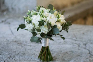 Beyaz düğün buketi şakayık, güller, lisianthus, frezya ve okalipus gri taş arka planda izole edilmiş..