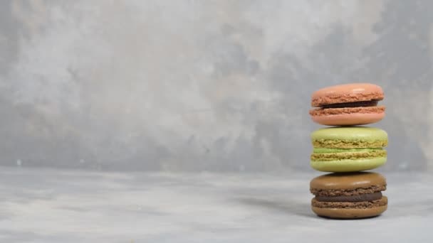 Boy estabelece três macaroons para tirar uma foto em fundo cinza. Macaroons em fundo cinza, coloridos biscoitos franceses macaroons. Layout criativo feito de macaroons coloridos. — Vídeo de Stock