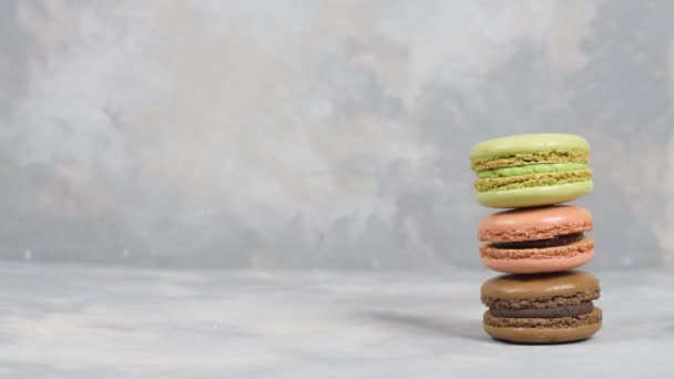 Boy estabelece três macaroons para tirar uma foto em fundo cinza. Macaroons em fundo cinza, coloridos biscoitos franceses macaroons. Layout criativo feito de macaroons coloridos. — Vídeo de Stock