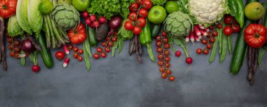 Farklı organik sebzeler - kuşkonmaz, domates vişne, avokado, enginar, biber, limon, limon, gri arka planda tuz. Çiğ vejetaryen konsepti.