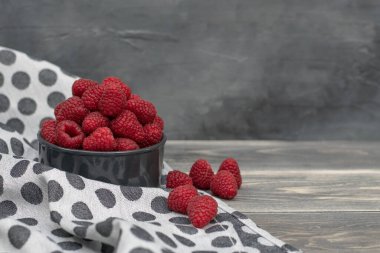 Gri ahşap arka planda kırmızı ahududular kasede. Taze meyve..