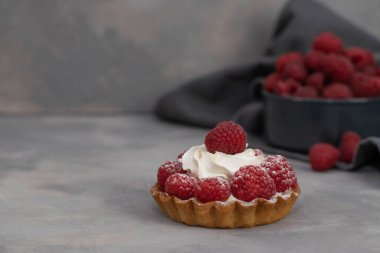 Tüm aile için lezzetli bir tatlı ve kolay bir diyet, mayasız ahududu sepeti ve üzerine pudra şekeri serpiştirilmiş tatlı. Gri arkaplan.