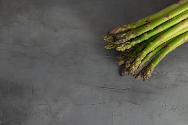 Koyu arkaplanda taze yeşil ve beyaz kuşkonmaz. Taze sebze..