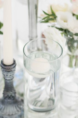 Resepsiyondaki düğün yemeği masasının yakın çekimi. Taze çiçekler ve ayna tabağında mumlar. Düğün süslemeleri. Masa süslemeleri.