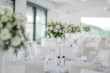 Masanın üzerinde yeşil yapraklar ve taze çiçeklerden yapılmış bir süs duruyor. Düğün günü. Taze çiçek süslemeleri. Şeftali ve beyaz takoz dekorasyonları.