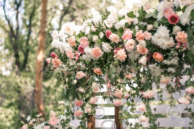 Düğün töreni. Çok güzel ve şık bir düğün kemeri, çeşitli taze çiçeklerle süslenmiş, bahçede duruyor..
