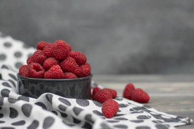 Gri ahşap arka planda kırmızı ahududular kasede. Taze meyve..