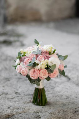 Gri desenli arka planda güzel bir gelin buketi beyaz ve pembe çiçekler ve yeşillik. Gül, ozothamnus, frezya ve lisianthus 'tan oluşan düğün buketi. Düğün günü..