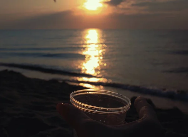 Gün batımında bir bardakla