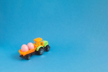 Mavi arka planda, traktör römorkunda Paskalya yumurtaları. 2021 'i hazırla..