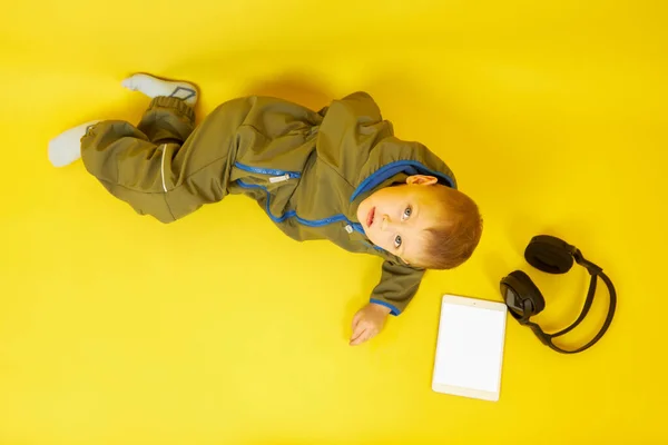 Een jongen met een koptelefoon speelt een digitale tablet — Stockfoto