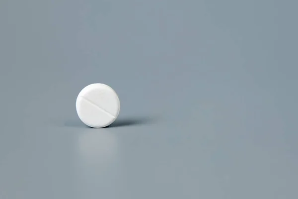 Píldora blanca redonda sobre fondo gris —  Fotos de Stock
