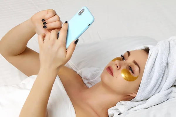 Seorang gadis dengan masker di bawah matanya melihat smartphone nya — Stok Foto