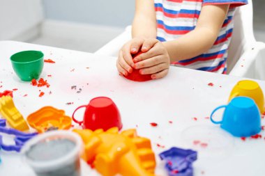Bir çocuğun elleri beyaz bir masada kinetik kumla oynar.