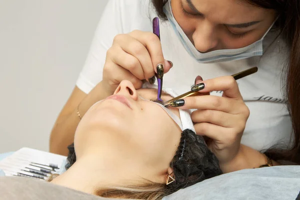 Cosmetologist executa o procedimento de extensão de pestanas com pinças — Fotografia de Stock