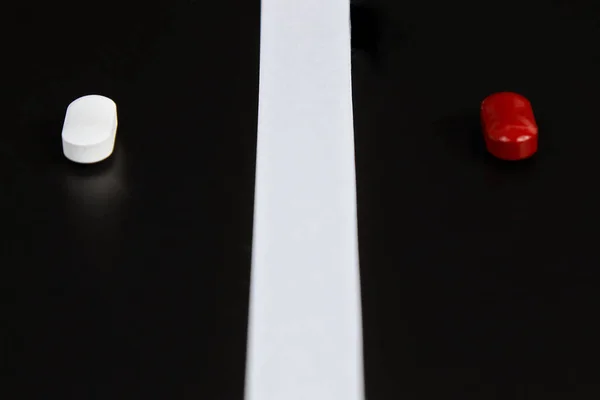 Белые и красные таблетки на черном фоне. — стоковое фото