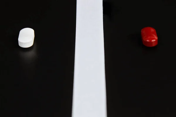 Pastillas blancas y rojas sobre fondo negro. — Foto de Stock