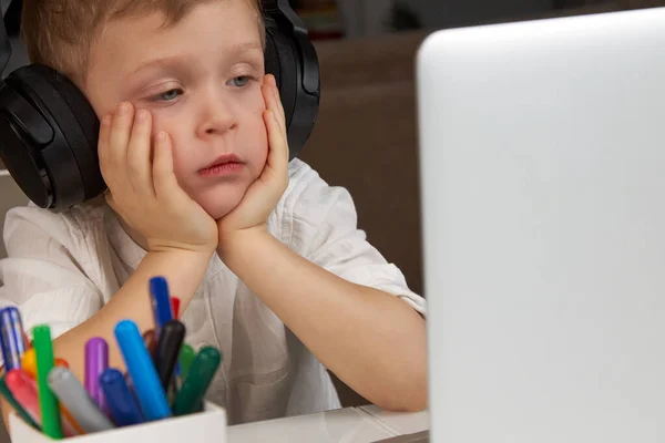 Ένα παιδί που φοράει ακουστικά κοιτάζει με προσοχή την οθόνη του φορητού υπολογιστή. — Φωτογραφία Αρχείου