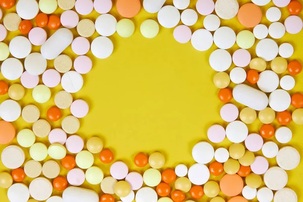 黄色の表面に様々なカラフルな錠剤のフレームのトップビュー — ストック写真