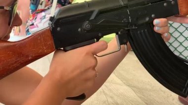 Bir kız atış poligonunda havalı tüfeği ateşliyor.