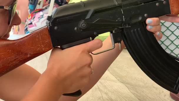 A girl pulls the trigger of an air rifle in a shooting gallery — Stock Video