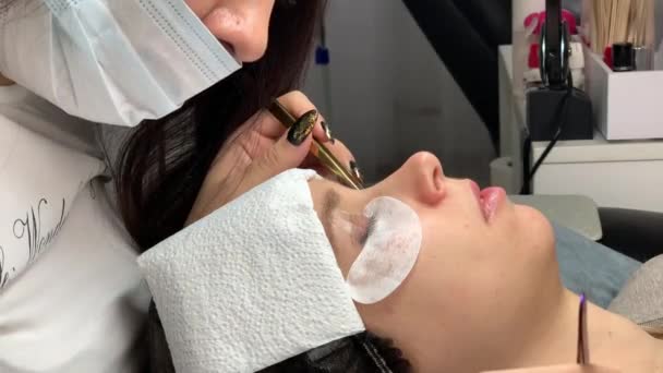 Cosmetologist performs the procedure of eyelash extension with tweezers — Stock Video
