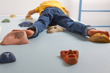 Çocuk kararlı bir şekilde tırmanma duvarına tırmanıyor.