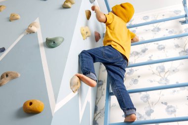 Çocuk tırmanma duvarına ve merdivenlerine tırmandı.