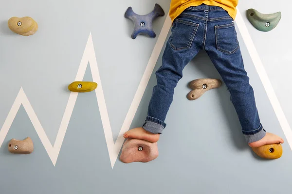 Los pies de los niños están en los ganchos de la pared de escalada — Foto de Stock