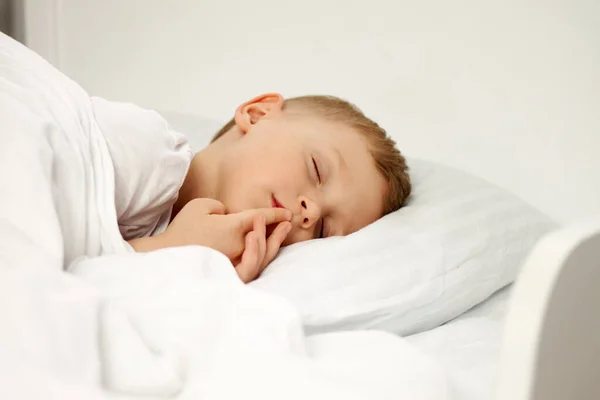 Il bambino dorme dolcemente su un lettino bianco. — Foto Stock