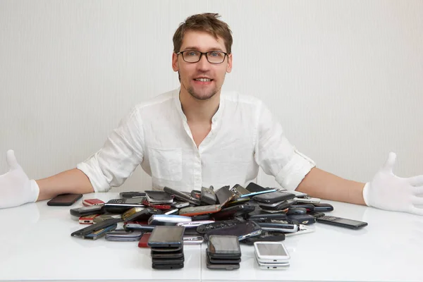 A smartphone repairman is happy to repair a huge pile of broken phones.