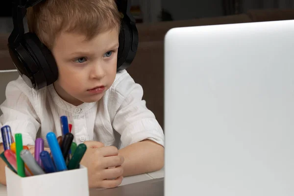 Κοντινό πλάνο ενός παιδιού που κάθεται μπροστά από ένα φορητό υπολογιστή με ακουστικά — Φωτογραφία Αρχείου