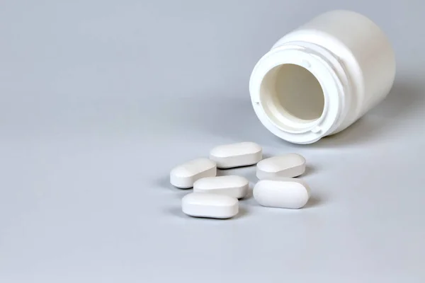 灰色の背景に点在する錠剤のボトル — ストック写真
