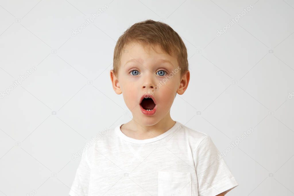 A small boy with blue eyes opened his mouth in surprise against