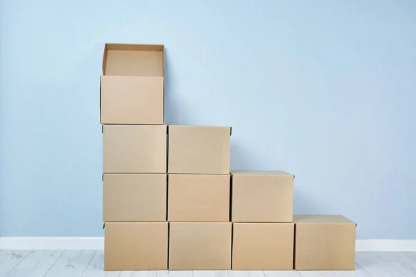 Cardboard boxes are lined with steps on a blue background — Stock Photo, Image