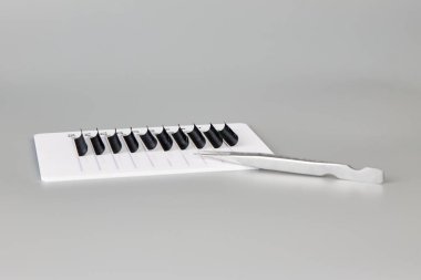 Gri arka planda takma kirpikli ve cımbızlı tablet.