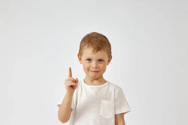 Un chico con una cara graciosa señala su dedo sobre un fondo blanco — Foto de Stock